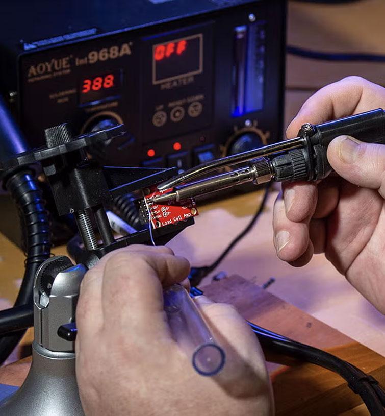 A person uses tools on a small metal chip